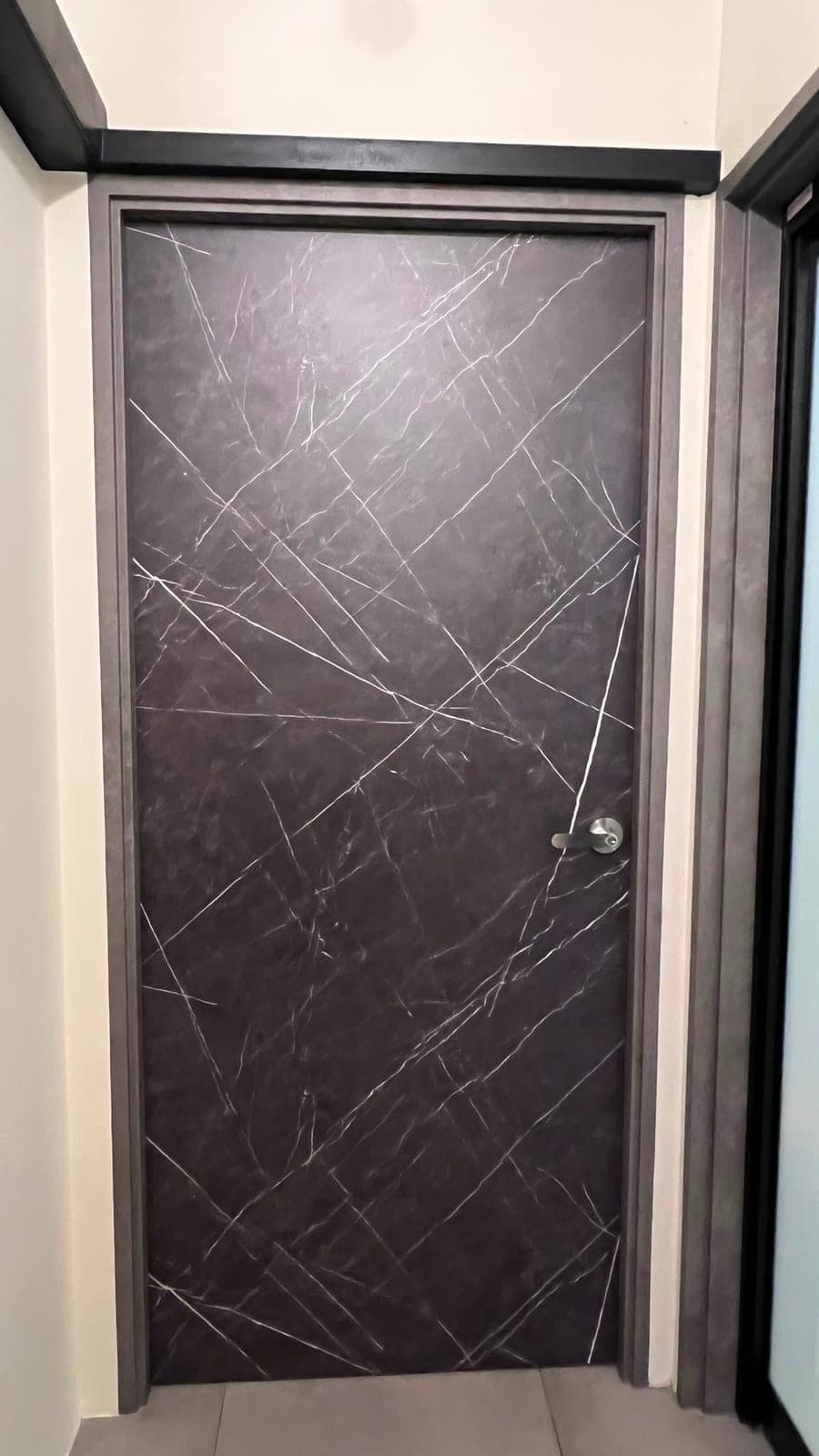 A bedroom door in Punggol wrapped in a black marble-look film