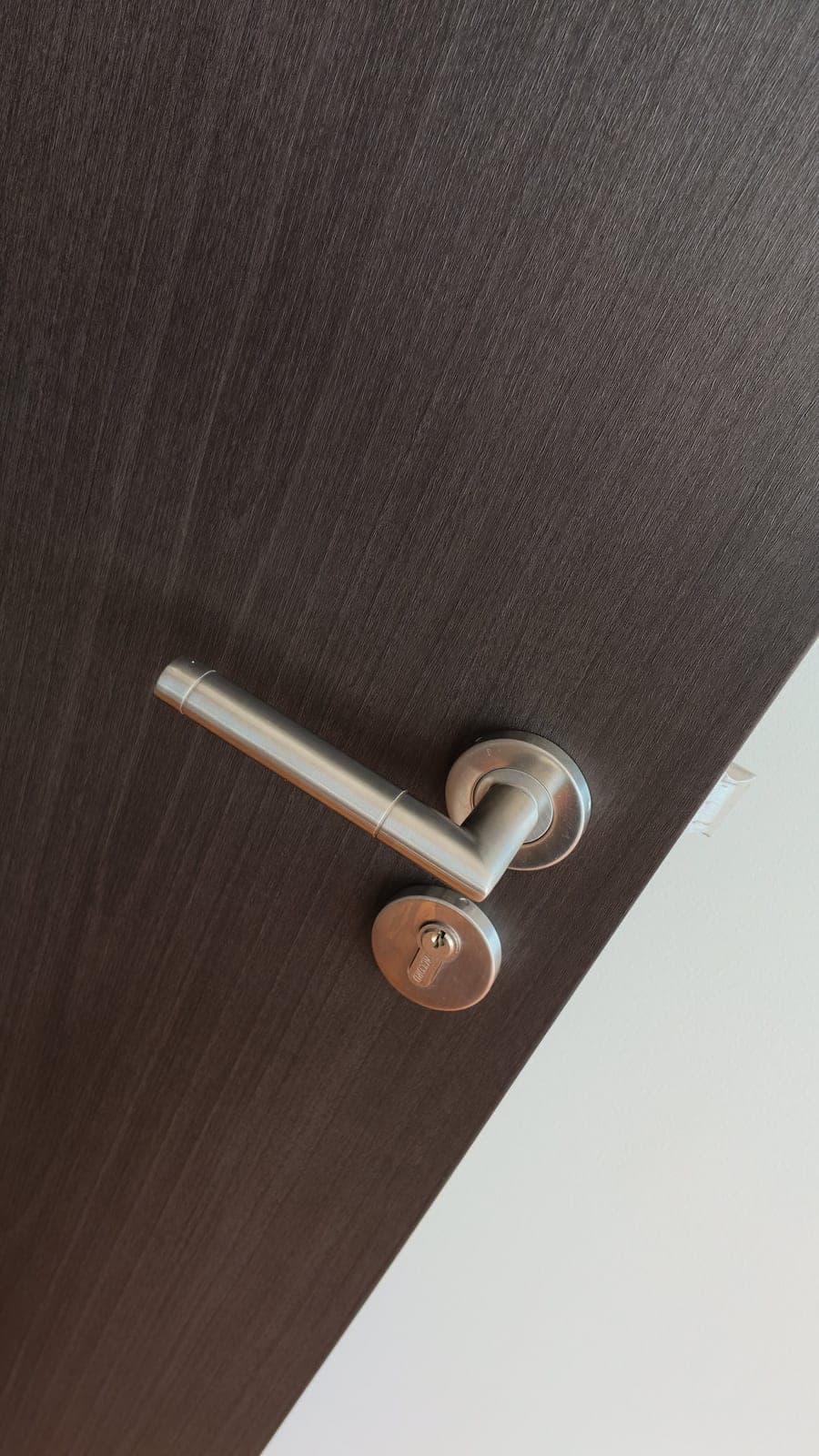 Dark wood-look film trimmed around a chrome lever handle