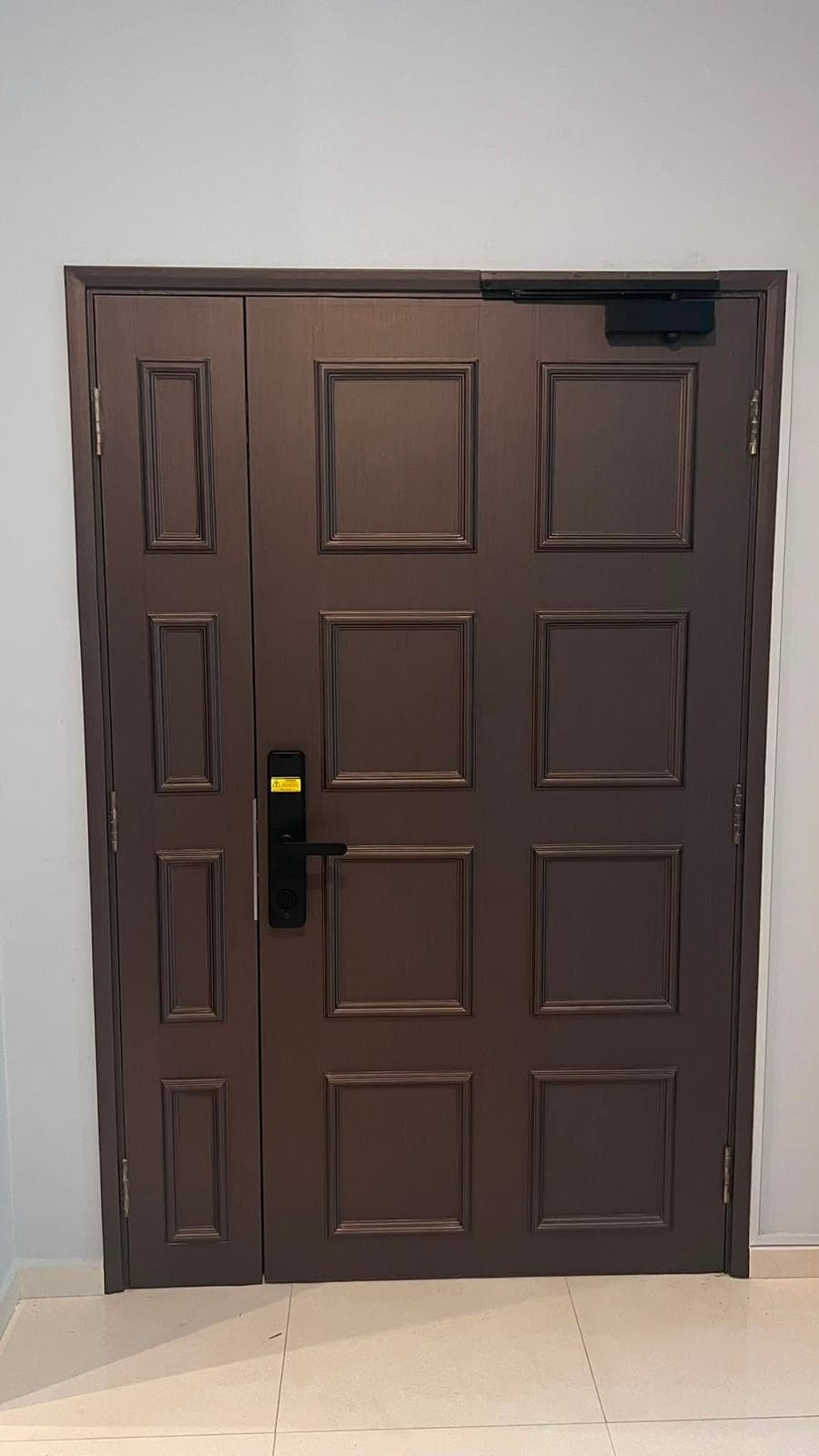 The double door wrapped in a dark brown wood-look film