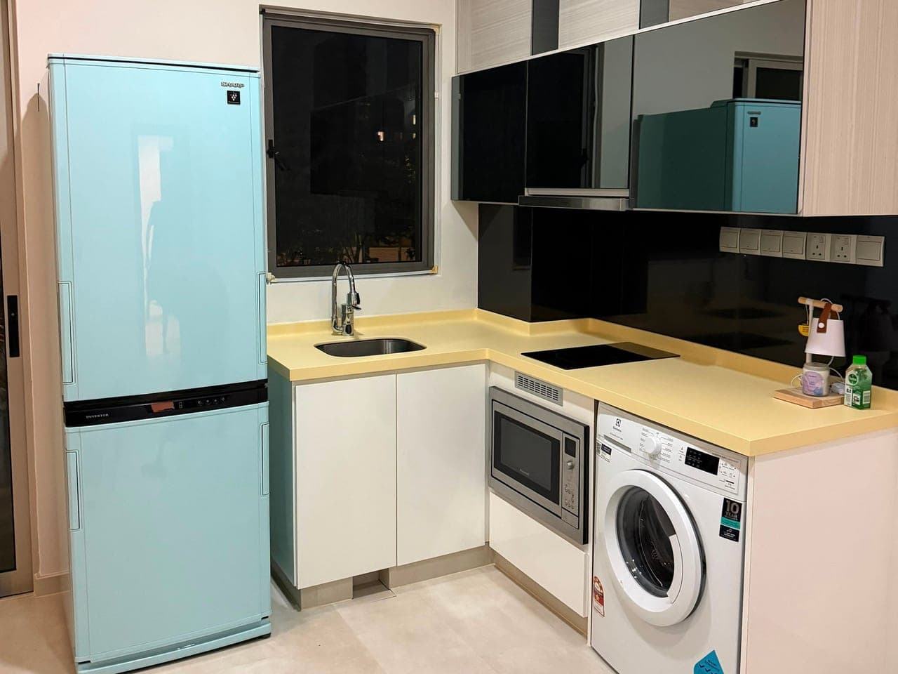The kitchen with the worktop wrapped in cream and the two-door fridge in pale blue