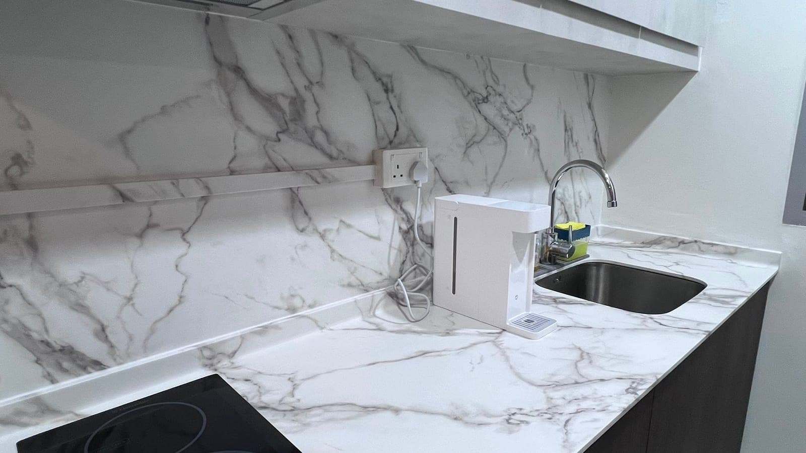 A white marble-look worktop and backsplash around a sink in Hougang