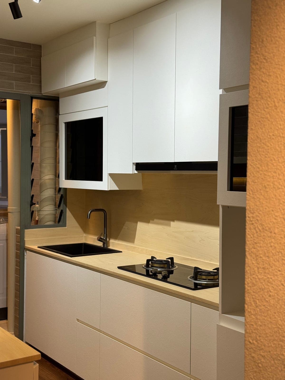 A galley kitchen in Punggol wrapped in white with a birch-look worktop