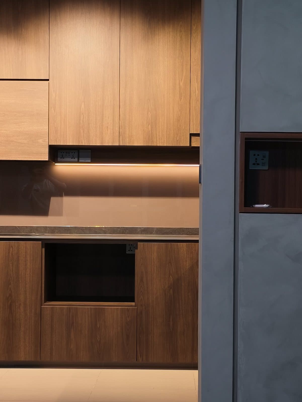 A walnut-look kitchen in Tampines with lighting under the cabinets
