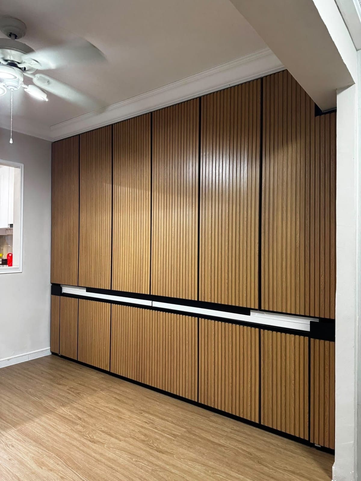 A wall of wardrobes in Bedok wrapped in a fluted wood-look film
