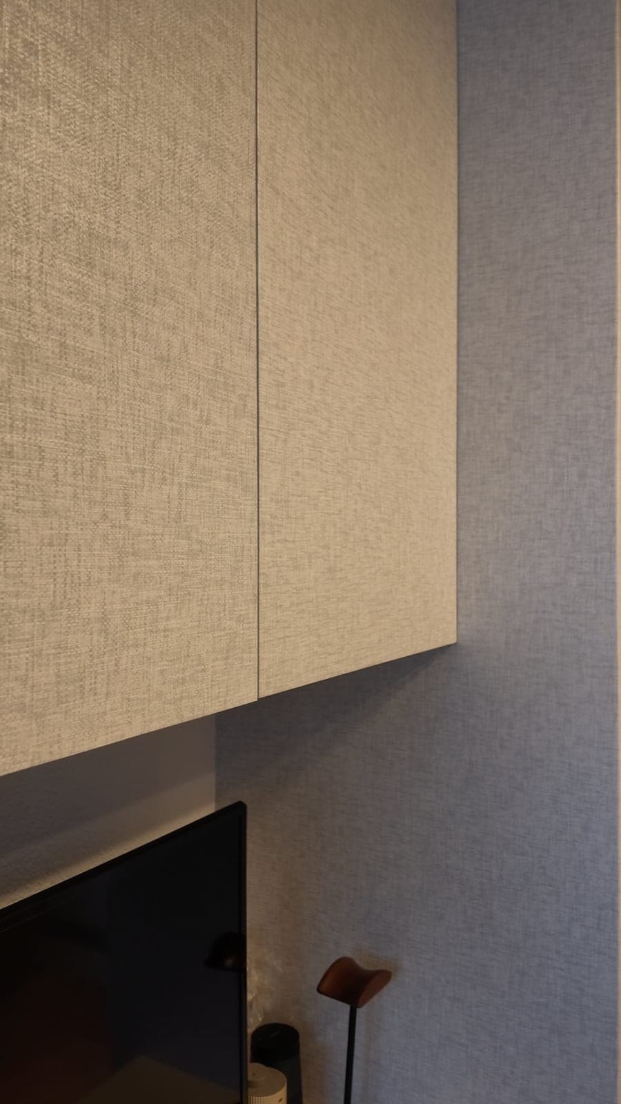 The upper cabinet doors wrapped in a pale beige linen-texture film